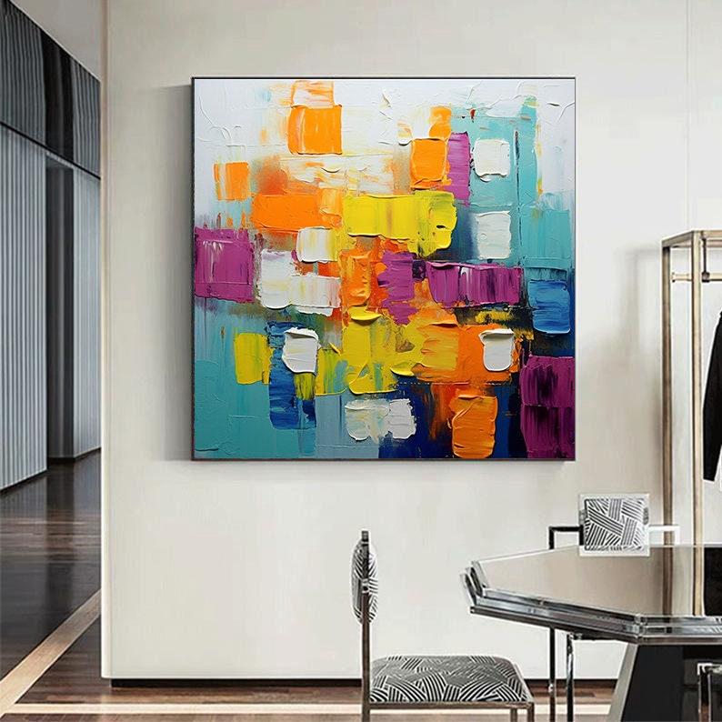 May include: Abstract painting with bold, colorful blocks of yellow, orange, purple, blue, and white paint. The painting has a textured, layered look, giving it a three-dimensional effect.