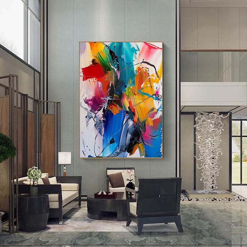Puede incluir: Pintura abstracta con trazos audaces de azul, amarillo, rojo, verde y rosa. La pintura est&aacute; enmarcada y colgada en una pared en un interior moderno.