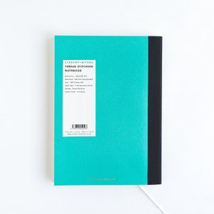 May include: A turquoise blue notebook with a black spine. The notebook is labeled "CLASSIKY+MITSOU THREAD STITCHING NOTEBOOK" and has the details: "Details/ 4842R-02 Book Cover: Soft Cover (Surgeline bind) Size: 148x210mm (A5) Paper Type:  Foolscap paper (80g/m2) Binding: Thread Stitching Surface Finish:  Wove/roughing"