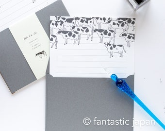 May include: A set of six letter papers and three envelopes with a black and white cow pattern. The paper has a gray border and the envelopes are gray. The text on the paper reads "Ah la la" and "letterpress 6 papers 3 envelopes".