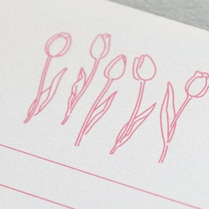 Puede incluir: Una tarjeta blanca con cinco dibujos de tulipanes rosas en l&iacute;nea. Los tulipanes est&aacute;n dispuestos en una fila a trav&eacute;s de la tarjeta.