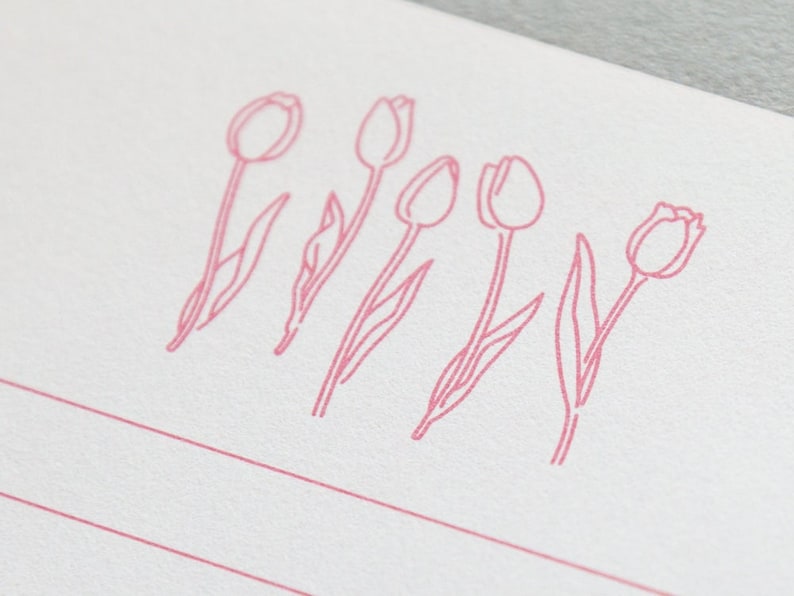 Puede incluir: Una tarjeta blanca con cinco dibujos de tulipanes rosas en l&iacute;nea. Los tulipanes est&aacute;n dispuestos en una fila a trav&eacute;s de la tarjeta.