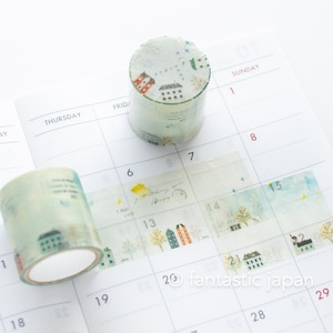 Könnte beinhalten: Zwei Rollen Washi-Tape mit hellblauem Hintergrund und Illustrationen von Häusern, Bäumen und Vögeln. Das Klebeband befindet sich auf einem weißen Kalender mit den aufgedruckten Zahlen 1, 6, 7, 8, 13, 14, 15, 20, 21, 28 und 29.