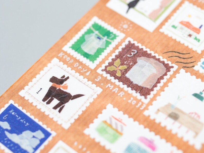 May include: A sheet of decorative washi tape featuring various illustrations, including a dog, a shirt, a flower, and a building. The tape is printed on a brown background with white borders and includes handwritten text such as "Keep Dry" and "3 Mar. 2013".