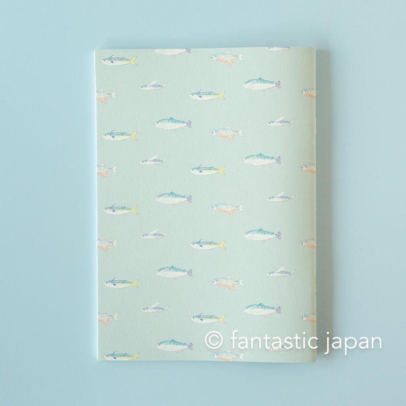 May include: A notebook with a light green cover featuring a repeating pattern of colorful fish illustrations. The fish are in shades of blue, yellow, and orange. The text "&copy; fantastic japan" is printed at the bottom.