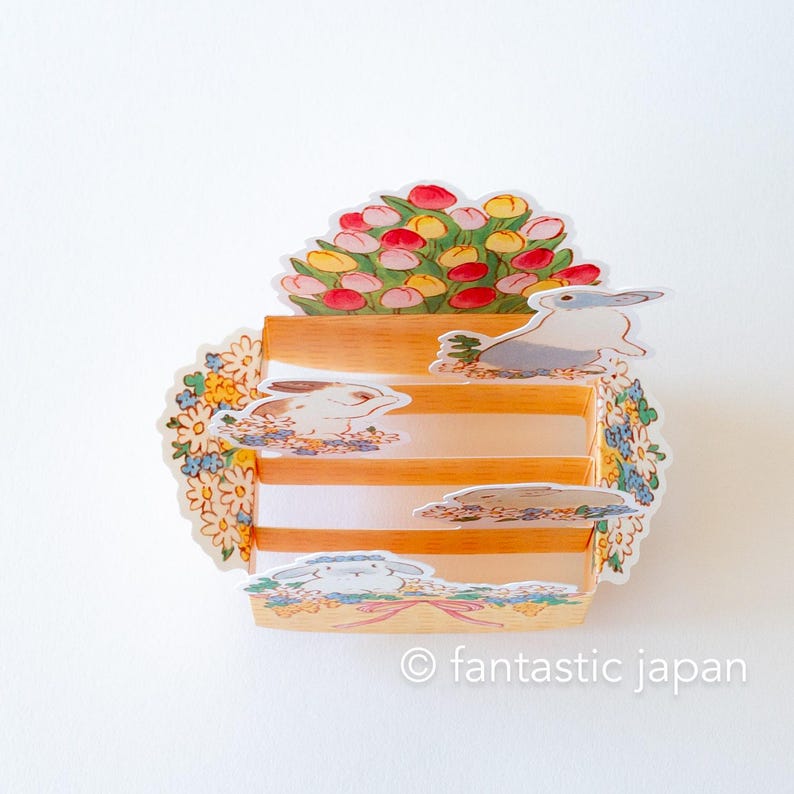 May include: A three-tiered paper stand with a floral design and bunny illustrations. The top tier features a bouquet of pink and yellow tulips. The stand is decorated with a floral border and the text "&copy; fantastic japan".