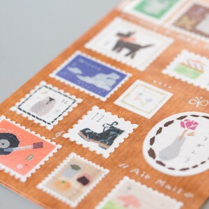 May include: A sheet of decorative stamps with various illustrations, including a boot, a bird, a cloud, a flower, and a record player. The stamps are printed on a brown background with white borders and the text "Air Mail" is printed on the bottom right corner.