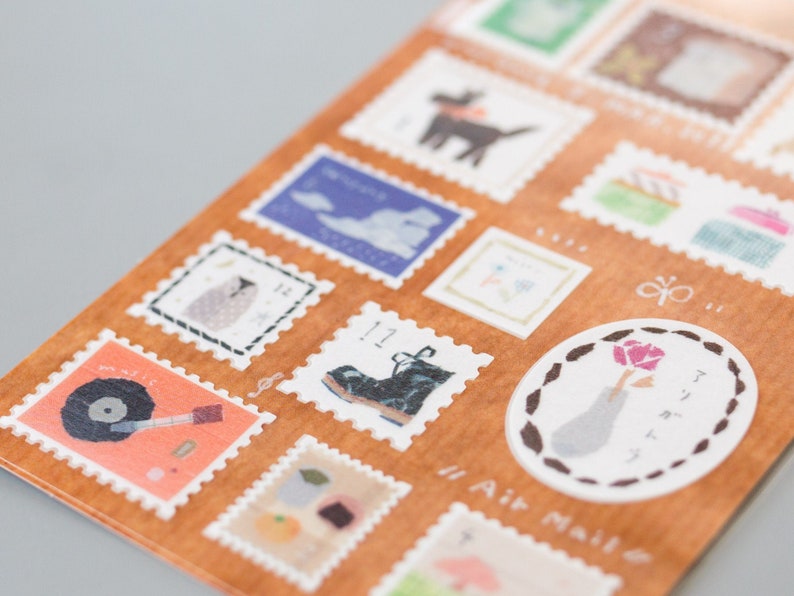 May include: A sheet of decorative stamps with various illustrations, including a boot, a bird, a cloud, a flower, and a record player. The stamps are printed on a brown background with white borders and the text "Air Mail" is printed on the bottom right corner.