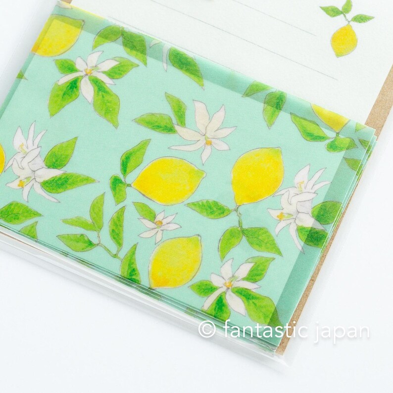 May include: A notepad with a light green cover featuring a watercolor design of yellow lemons, white blossoms, and green leaves. The text "fantastic japan" is printed in the bottom corner. The notepad is open, revealing blank pages.