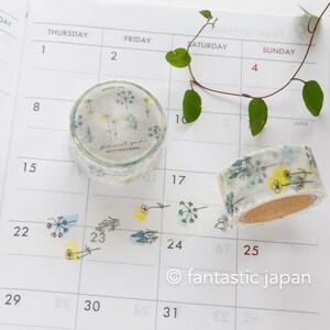 Puede incluir: Dos rollos de cinta washi con un patr&oacute;n floral. La cinta es blanca con flores y hojas verdes y amarillas. El texto en la cinta dice "Botanical Garden" y "Motif Paper Works".