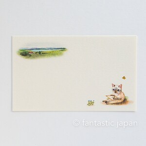 May include: A cream-colored stationery card featuring a watercolor illustration. The card depicts a landscape scene with a house, trees, and a lake. A cat is sitting on the grass, holding a paper, with a butterfly nearby. The text "fantastic japan" is at the bottom.