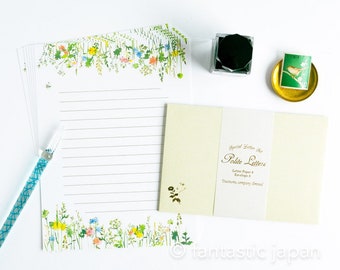 Pode incluir: Conjunto de papelaria com papel de carta pautado e envelopes com uma borda floral. Inclui um tinteiro preto, um prato dourado com um selo verde e uma caneta. O conjunto de papelaria é rotulado como "Special Letter Set Petite Letters".