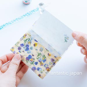 May include: A small, floral-patterned envelope with a matching lined card. The envelope features a translucent design with blue, purple, and yellow flowers on a cream background. The card has a small floral illustration in the corner.