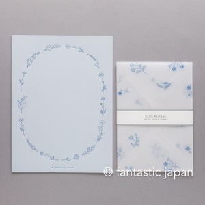 Pode incluir: Um conjunto de papelaria azul claro com um design floral. O conjunto inclui uma folha grande de papel com uma borda floral azul e um envelope correspondente com um padr&atilde;o floral. O texto "BLUE FLORAL" e "HUTTE PAPER WORKS" s&atilde;o vis&iacute;veis.