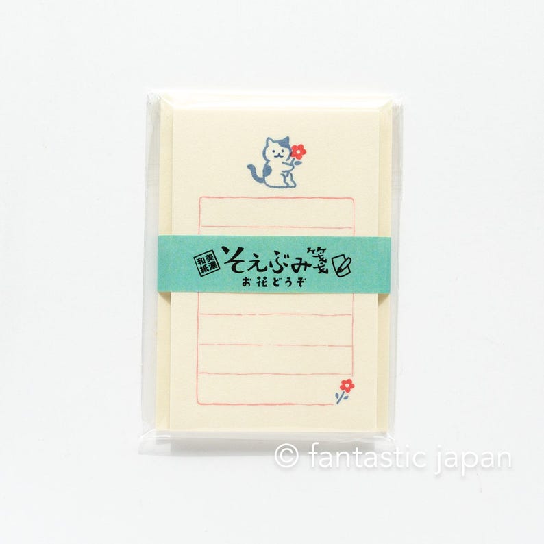 Puede incluir: Un paquete de tarjetas de notas con l&iacute;neas con un lindo gato de dibujos animados sosteniendo una flor. Las tarjetas son de color crema con un borde azul claro y l&iacute;neas rojas. El texto en el frente de las tarjetas dice "Gracias" en japon&eacute;s.