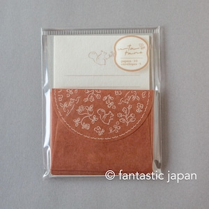 May include: A stationery set featuring a cream-colored card and a rust-colored envelope with a white floral and squirrel design. The set includes 10 papers and 5 envelopes, packaged in a clear plastic sleeve. The text "uta fame" is visible.