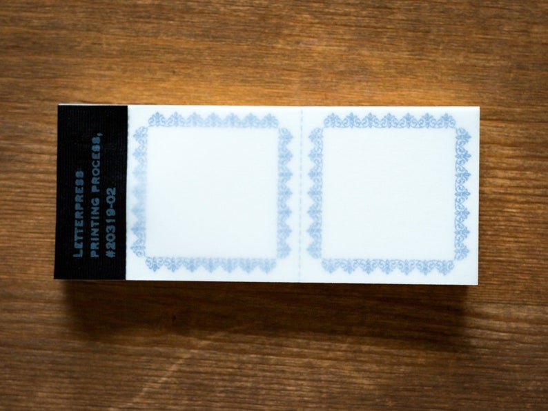 Puede incluir: Dos etiquetas blancas en blanco con bordes decorativos azules. Las etiquetas est&aacute;n unidas a un fondo negro con el texto "LETTERPRESS PRINTING PROCESS #20319-02".