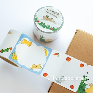 Puede incluir: Un rollo de cinta washi con fondo blanco y un patrón repetido de un conejo marrón saltando a través de una vid verde con fresas rojas. El texto "ロール付箋" y "PAPIER PLATZ" está impreso en dorado en la cinta. La cinta está enrollada y se encuentra sobre una superficie blanca. Hay un segundo rollo de cinta washi con fondo blanco y un patrón repetido de un conejo amarillo saltando a través de una nube azul con plátanos. El texto "fantastic japan" está impreso en negro en la cinta. La cinta está enrollada y se encuentra sobre una caja de cartón marrón.