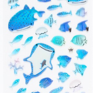 May include: A sheet of blue and white stickers featuring various sea creatures, including a whale shark, jellyfish, and fish. The stickers are ideal for adding a touch of whimsy to journals, planners, or other craft projects.
