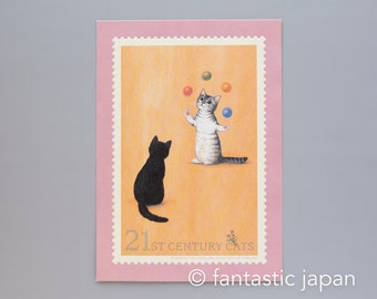 May include: A postcard featuring a whimsical illustration of two cats. One black cat sits, while the other, a gray tabby, juggles colorful balls. The postcard has a pink border and text that reads "21st Century Cats."