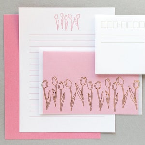 Puede incluir: Un juego de papeler&iacute;a rosa con un dise&ntilde;o de tulip&aacute;n dorado. El juego incluye una hoja de papel rayado, una tarjeta en blanco y un sobre rosa.
