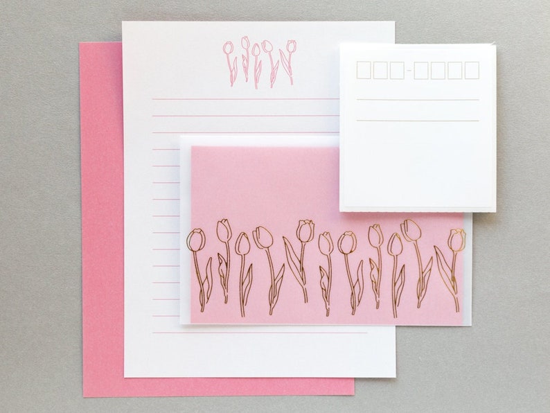 Puede incluir: Un juego de papeler&iacute;a rosa con un dise&ntilde;o de tulip&aacute;n dorado. El juego incluye una hoja de papel rayado, una tarjeta en blanco y un sobre rosa.