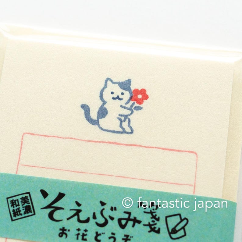 Puede incluir: Un gato azul y blanco sosteniendo una flor roja con el texto "そえぶみ箋" en japon&eacute;s, que se traduce como "papel de carta". El texto "fantastic japan" tambi&eacute;n es visible en la imagen.