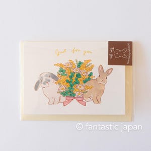 May include: A greeting card featuring a yellow and white floral bouquet, two rabbits, and the text "Just for you".