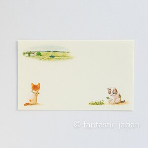 May include: A cream-colored stationery card featuring watercolor illustrations of two cats and a rural landscape. One cat is orange and white, the other is gray and white. The card has the text "fantastic japan" at the bottom.