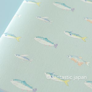 May include: A light blue notebook with a repeating pattern of watercolor fish in shades of blue, yellow, and purple. The text "fantastic japan" is in the lower right corner.