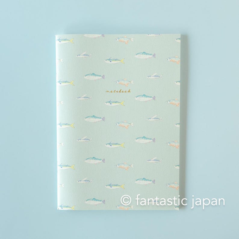 May include: A notebook with a light green cover featuring a pattern of colorful fish illustrations. The word "notebook" is written in a delicate script. The bottom right corner has the text "fantastic japan".