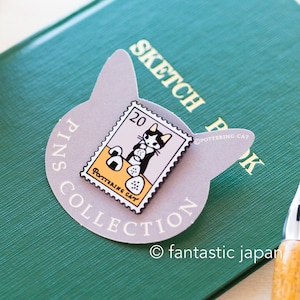 Pode incluir: Um alfinete roxo em forma de gato com o texto "PINS COLLECTION" e "SKETCH BOOK" nele. O alfinete apresenta um gato preto e branco comendo uma bola de arroz com o texto "20" e "POTTERING CAT" nele.