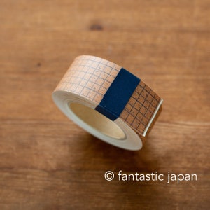 May include: A roll of decorative tape with a grid pattern in dark blue on a tan background. A dark blue band secures the roll. The tape is on a wooden surface. The text "fantastic japan" is at the bottom.