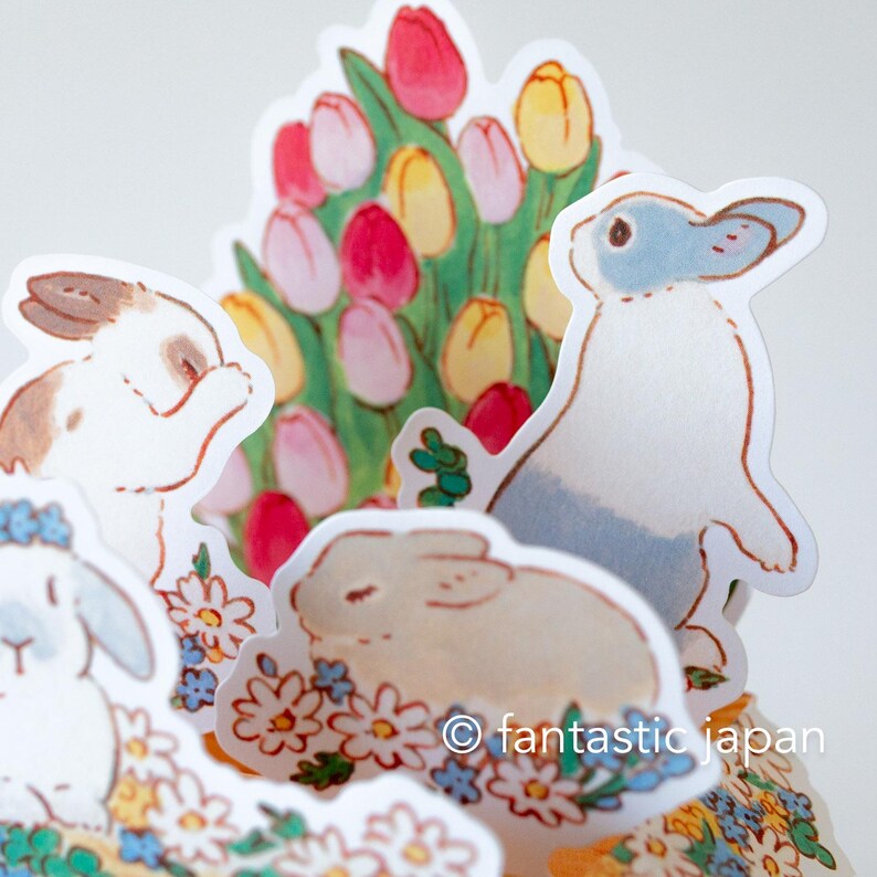 May include: A set of colorful paper stickers featuring cute bunnies and flowers. The stickers are perfect for adding a touch of whimsy to journals, planners, and other craft projects.