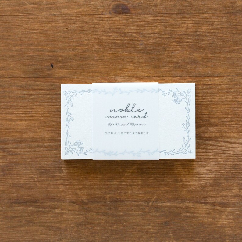 May include: A white box of 8.5 x 4.7 cm memo cards with a blue floral border and the text "noble memo card 8.5 x 4.7cm / 40 piece OEDA LETTERPRESS" printed on the front.