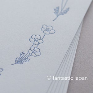 Pode incluir: Uma pilha de papel azul claro com um delicado desenho floral em tinta azul. O desenho apresenta pequenas flores e raminhos, com o texto "fantastic japan" no canto inferior direito.