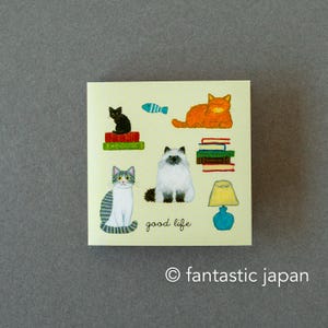 May include: A square sticker featuring illustrations of various cats, books, a fish, and a lamp. The text "good life" is written in a script font. The sticker has a light yellow background with the text "fantastic japan" at the bottom.