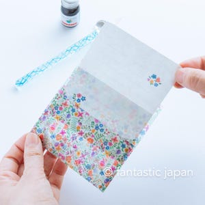 May include: A floral patterned stationery set featuring a lined writing sheet and matching envelope. The envelope is decorated with a colorful flower print. A glass pen and ink bottle are also visible.