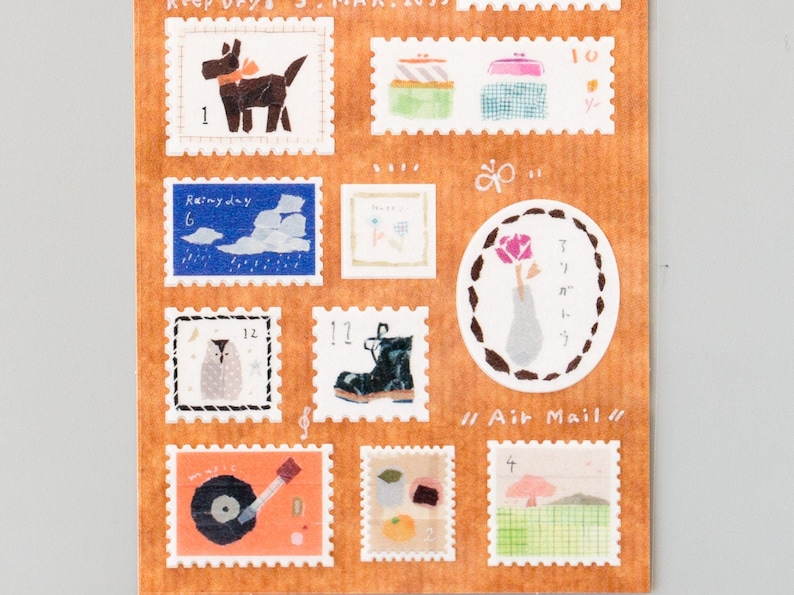 May include: A sheet of colorful illustrated stamps with various designs, including a dog, a boot, a vase with a flower, a record player, and a mushroom. The stamps are labeled with numbers and have a "Air Mail" label.