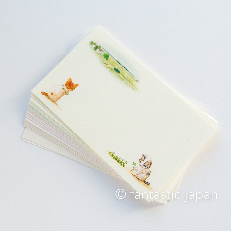 May include: A stack of cream-colored stationery featuring watercolor illustrations of playful kittens and a rural landscape. The stationery has a delicate, artistic feel, with the text "fantastic japan" at the bottom.