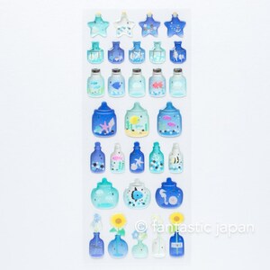 Puede incluir: Una hoja de pegatinas coloridas con botellas de vidrio azul que contienen varias criaturas marinas. Las pegatinas est&aacute;n dispuestas en filas e incluyen estrellas de mar, peces, medusas e hipocampos. El texto "fantastic japan" est&aacute; impreso en la esquina inferior derecha.