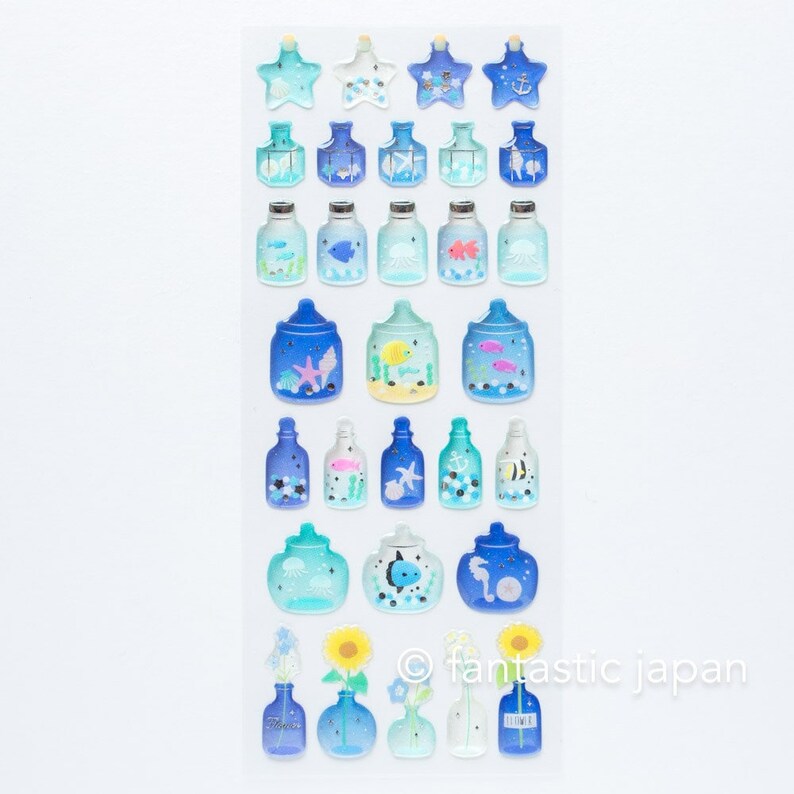 Puede incluir: Una hoja de pegatinas coloridas con botellas de vidrio azul que contienen varias criaturas marinas. Las pegatinas est&aacute;n dispuestas en filas e incluyen estrellas de mar, peces, medusas e hipocampos. El texto "fantastic japan" est&aacute; impreso en la esquina inferior derecha.