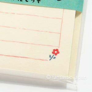 Puede incluir: Un paquete de tarjetas de notas con l&iacute;neas y una ilustraci&oacute;n de una flor roja. Las tarjetas son de color crema con l&iacute;neas rosas y una flor roja con un tallo azul.