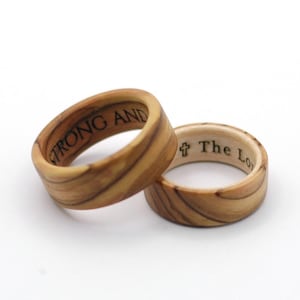 May include: Two wooden rings with engraved text. The ring on the left has the words "Strong and" engraved on it. The ring on the right has a cross and the words "The Lord" engraved on it.