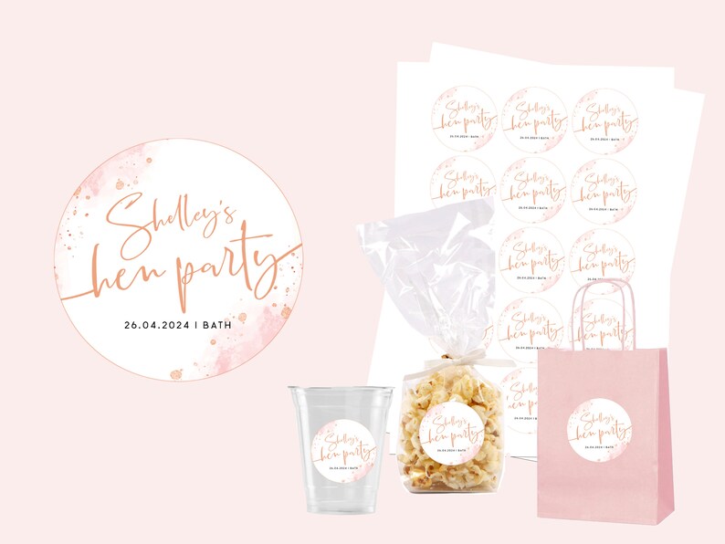 May include: A pink and gold round sticker with the text "Shelley's hen party 26.04.2024 | BATH" in a script font. The sticker has a watercolor background with pink and gold splatters.