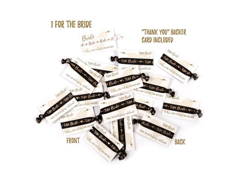 May include: A pile of black and gold hair ties with a white card attached to each one. The card says "Team Bride" and "Thank you for helping celebrate".