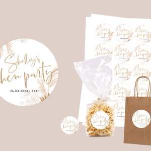 May include: A set of round, white stickers with gold lettering and a floral design. The stickers say "Shelly's hen party 26.04.2024 | BATH".
