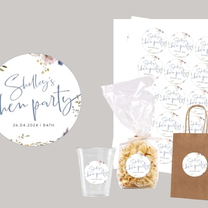 May include: A set of round, white stickers with a floral design and the text "Shelley's hen party 26.04.2024 | BATH" in blue script. The stickers are perfect for decorating party favors or gifts.