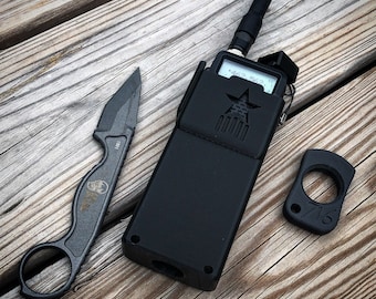 May include: A black two-way radio with a star and stripes design on the front. The radio has a black antenna and a black case. There is also a small black knife and a black key chain with a ring.