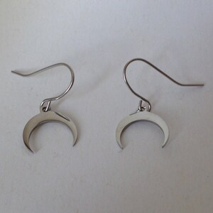 May include: A pair of silver crescent moon earrings with a simple hook design.